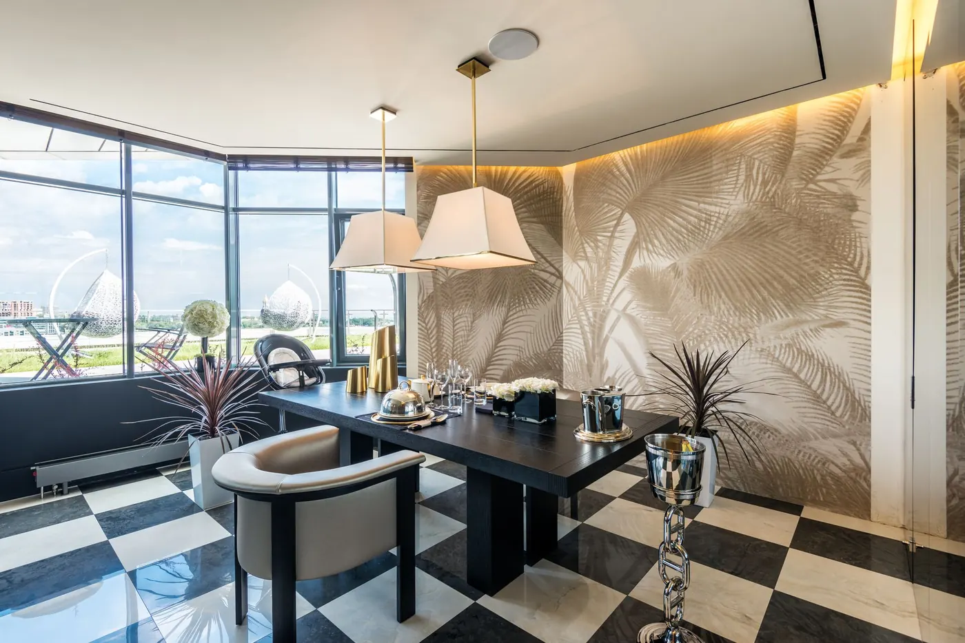 Bright dining area with a bold palm-leaf wallpaper accent wall and checkerboard marble floor