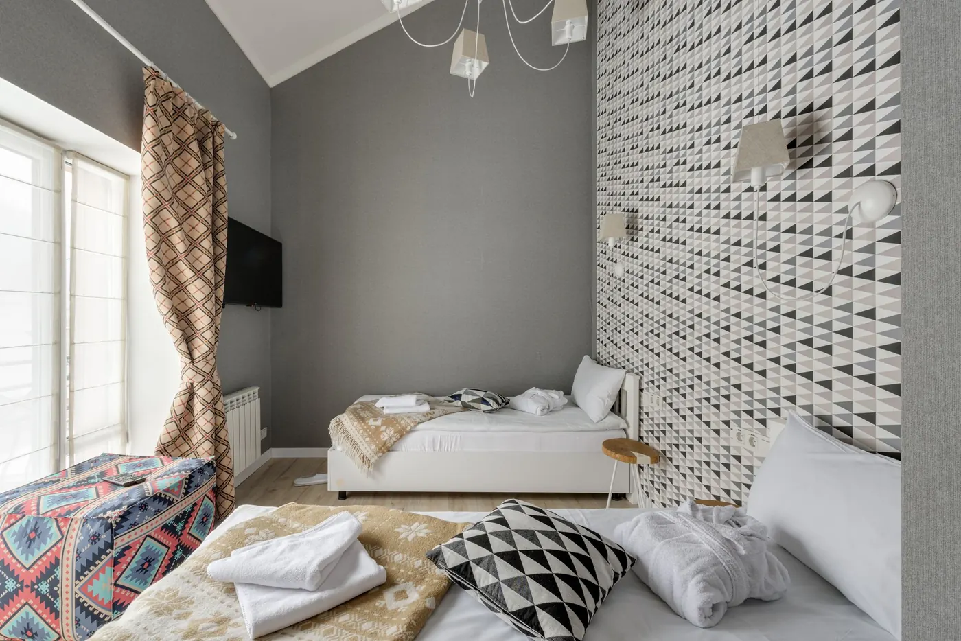Contemporary bedroom with a geometric triangle-patterned accent wall in soft neutral tones