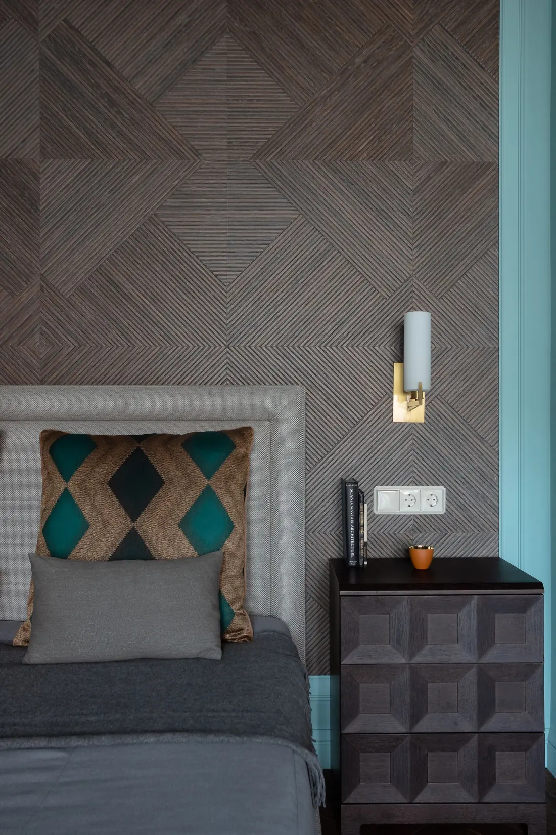 Bedroom with a dark textured geometric wallcovering above a wood nightstand
