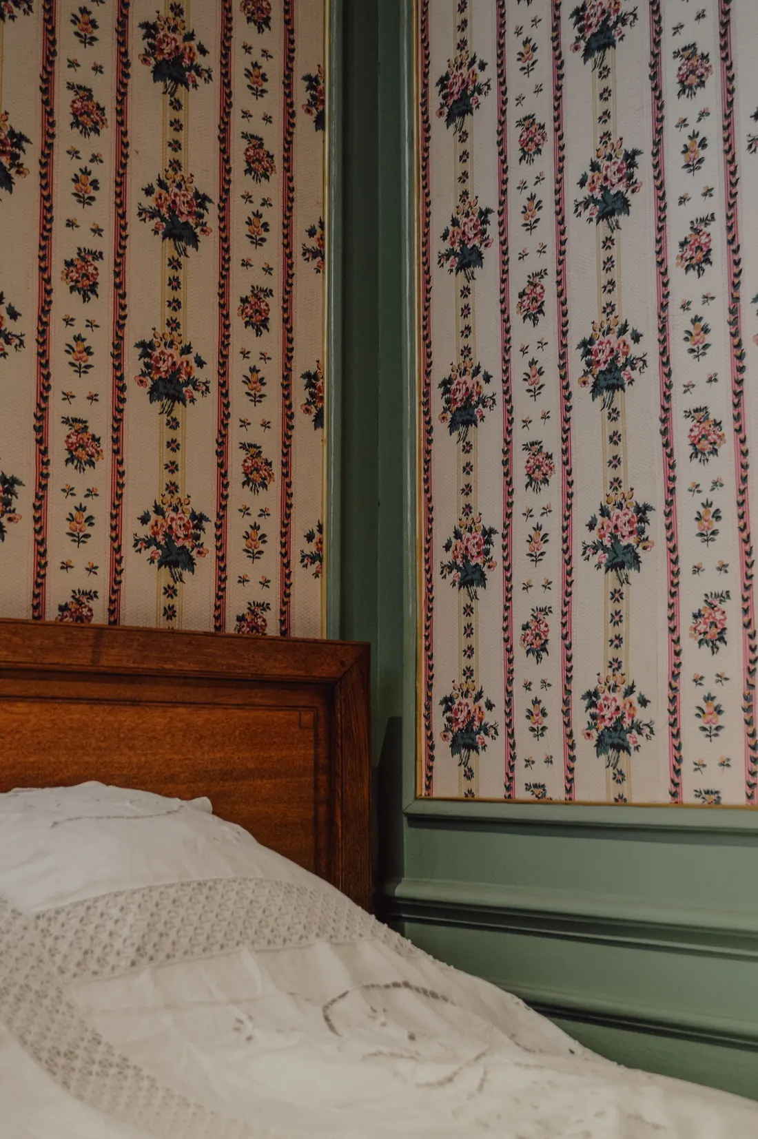 Classic striped floral wallpaper beside a traditional wood headboard