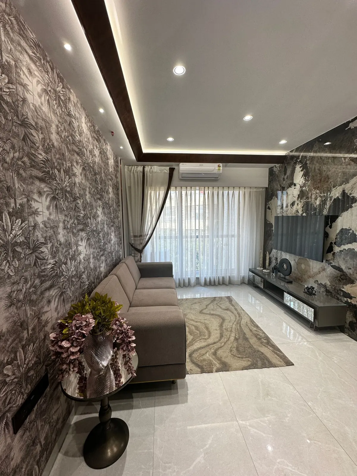 Living room with a dramatic dark botanical mural wallpaper beside a veined stone accent wall